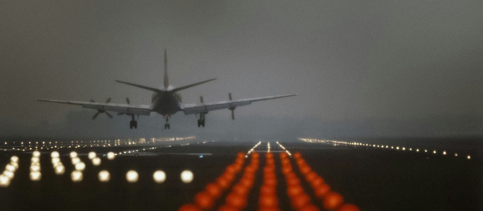 Avión aterrizando al anochecer con las luces de la pista